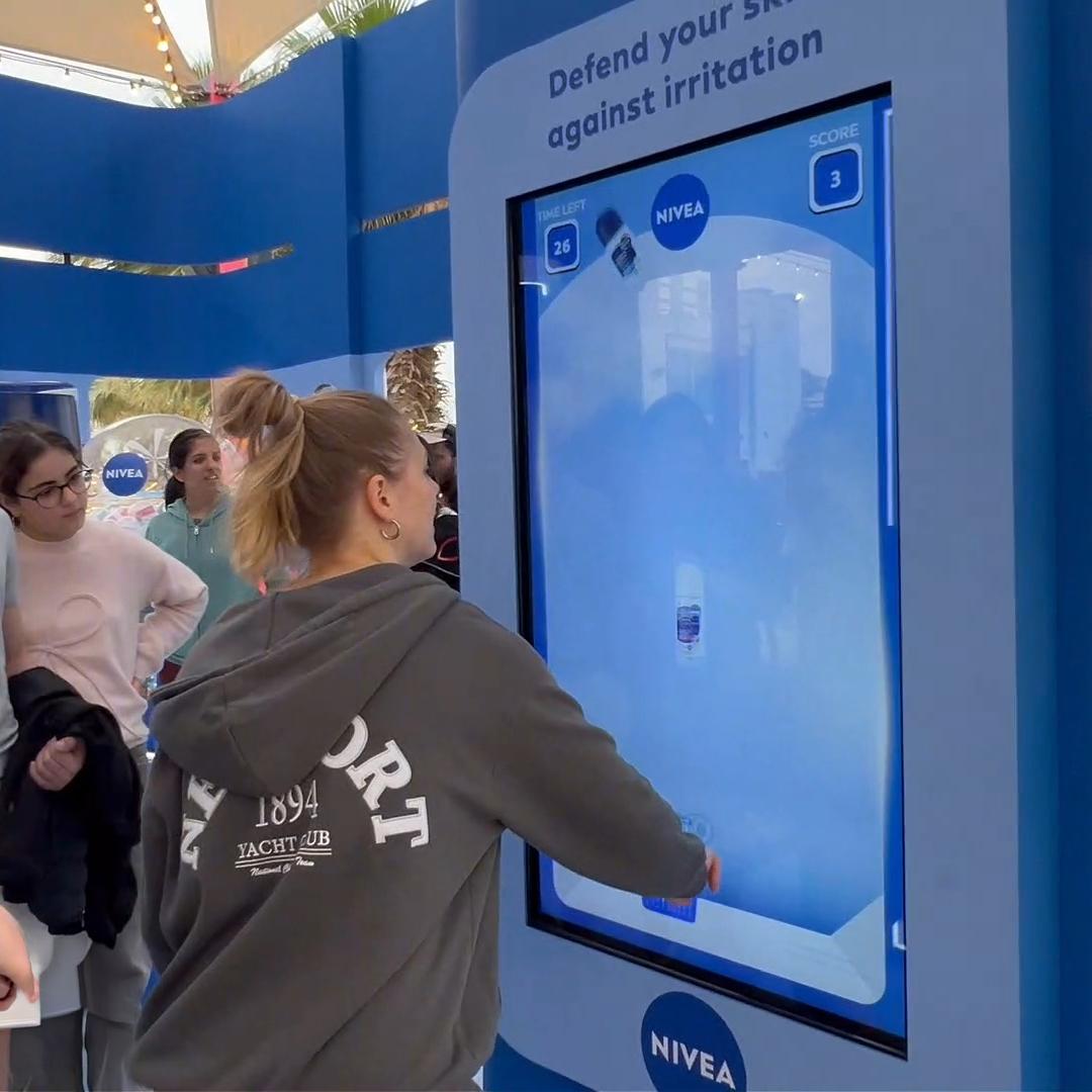 Guests playing the interactive Catch and Dodge game at a Niveae event in Dubai. Custom branded screen with data capture for exhibition marketing