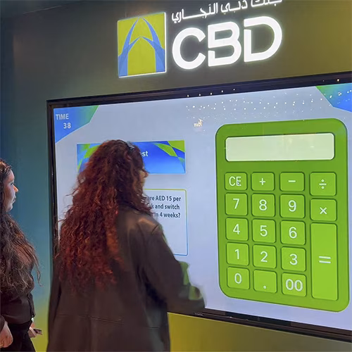 People playing a multi-level interactive financial literacy game at a brand activation event in Dubai, learning how to save and invest money.