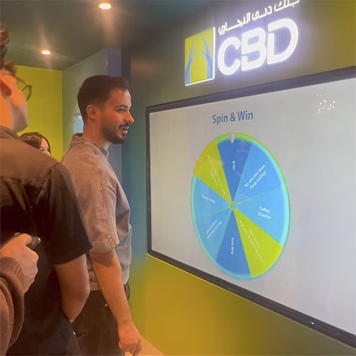 People playing a multi-level interactive financial literacy game at a brand activation event in Dubai, learning how to save and invest money.