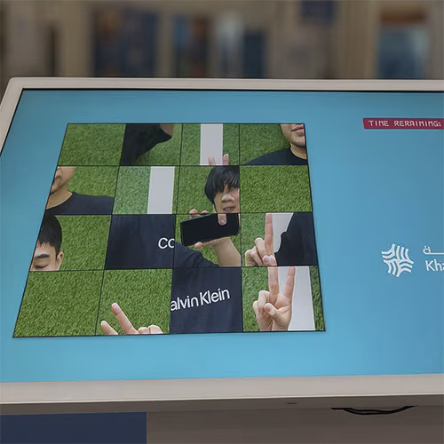 Guest solving a scrambled photo puzzle on a touchscreen at an event. Interactive image puzzle game rental for exhibitions, corporate events, and activations in Dubai.