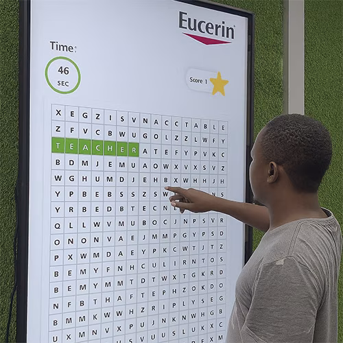 Guest playing interactive word search game at corporate event in Dubai, with branded screen, vibrant green backdrop