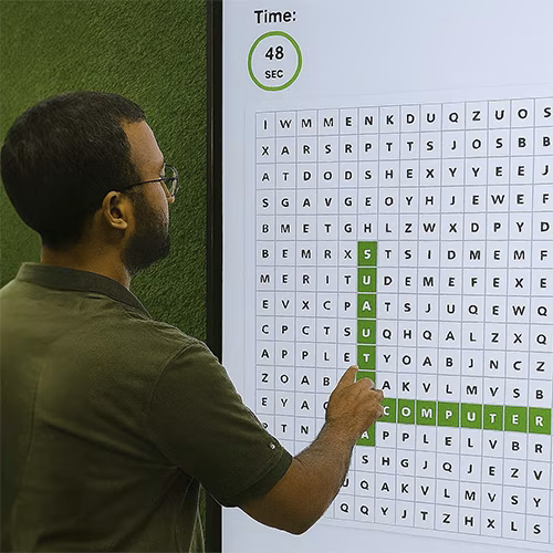 Guest playing interactive word search game at corporate event in Dubai, with branded screen, vibrant green backdrop