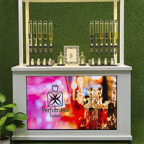 Perfume Booth setup in Dubai featuring a branded fragrance bar with colorful dispensers, interactive screen, and artificial grass backdrop for events and exhibitions