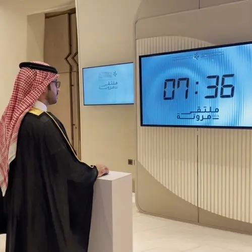 Guests playing Stop the Time interactive stopwatch game at a corporate event booth in Dubai, engaging with branded screen and trying to press the button at the perfect moment