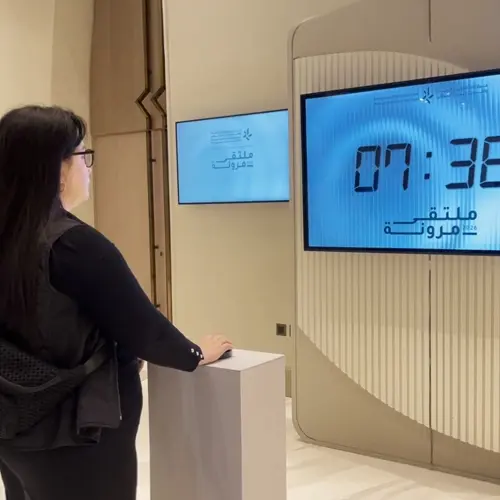 Guests playing Stop the Time interactive stopwatch game at a corporate event booth in Dubai, engaging with branded screen and trying to press the button at the perfect moment