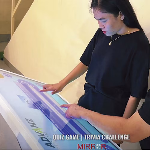 Touchscreen showing quiz results and a Dubai tower trivia question, with answer options and a person in a dark shirt standing beside the screen