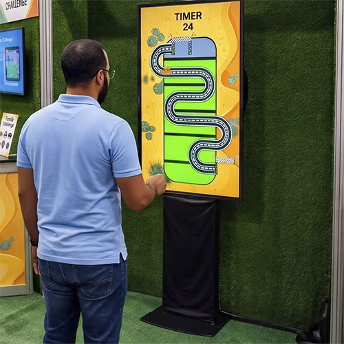 Guests playing the Interactive Camel Race in Dubai, running on custom foot pads to make digital camels sprint across a massive LED screen at a live event.