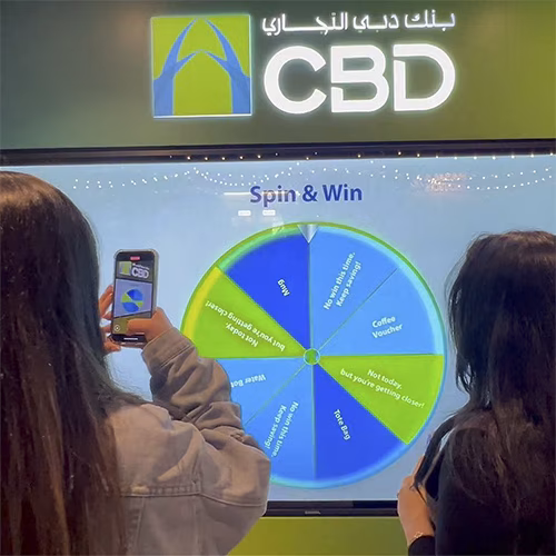 People playing a multi-level interactive financial literacy game at a brand activation event in Dubai, learning how to save and invest money.