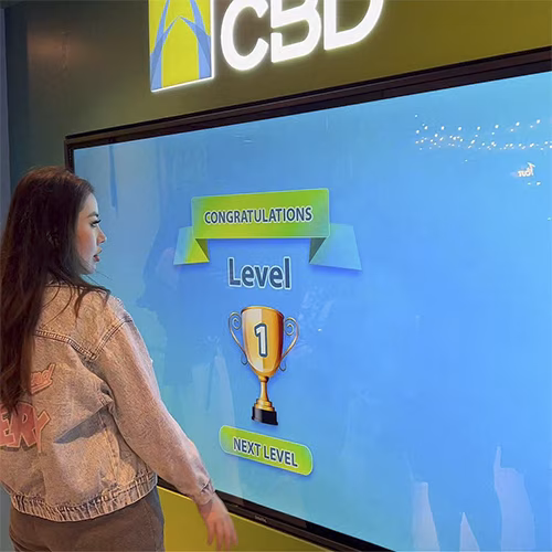 People playing a multi-level interactive financial literacy game at a brand activation event in Dubai, learning how to save and invest money.