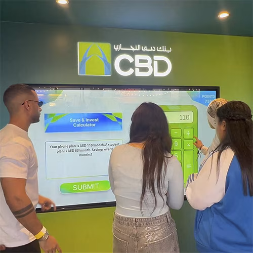 People playing a multi-level interactive financial literacy game at a brand activation event in Dubai, learning how to save and invest money.