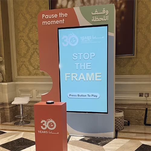 Guests playing Freeze the Frame interactive game at a corporate event in Dubai, focusing on screen visuals and pressing the button to stop the image at the perfect moment.