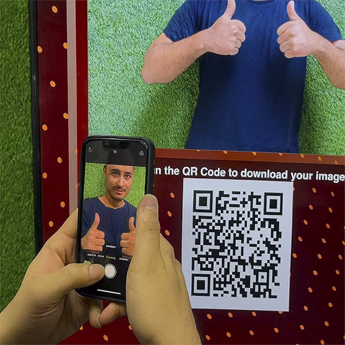Guest playing interactive event game at exhibition booth in Dubai, pressing button to win prize, with branded screen display and selfie sharing feature for engagement.