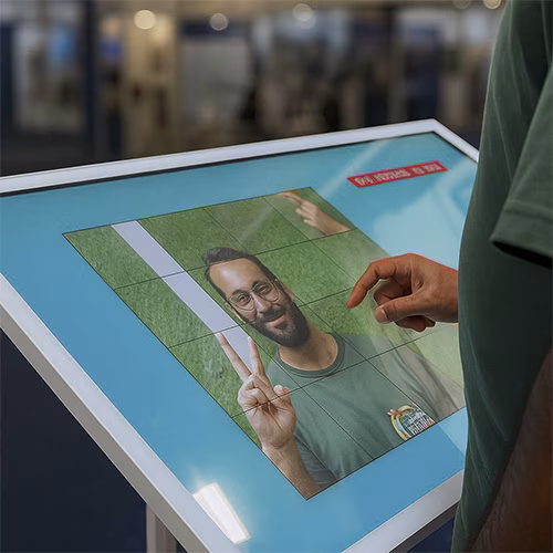 Guest solving a scrambled photo puzzle on a touchscreen at an event. Interactive image puzzle game rental for exhibitions, corporate events, and activations in Dubai.