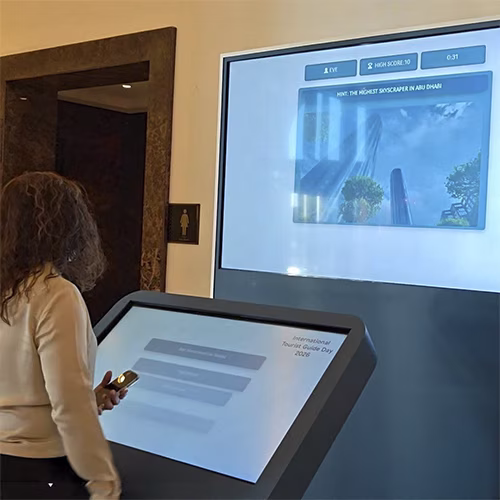 Multi-screen interactive UAE landmark guessing game display with custom branded interface for immersive event activation and digital tourism engagement.
