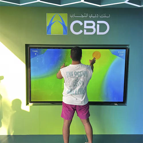 Interactive multi-level touch screen game rental at Dubai 30x30 event, showing guests engaged in a gamified fitness and financial literacy challenge.