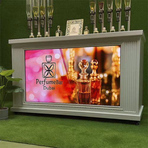 Perfume Booth setup in Dubai featuring a branded fragrance bar with colorful dispensers, interactive screen, and artificial grass backdrop for events and exhibitions