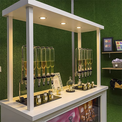 Perfume Booth setup in Dubai featuring a branded fragrance bar with colorful dispensers, interactive screen, and artificial grass backdrop for events and exhibitions