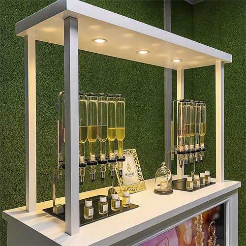 Perfume Booth setup in Dubai featuring a branded fragrance bar with colorful dispensers, interactive screen, and artificial grass backdrop for events and exhibitions