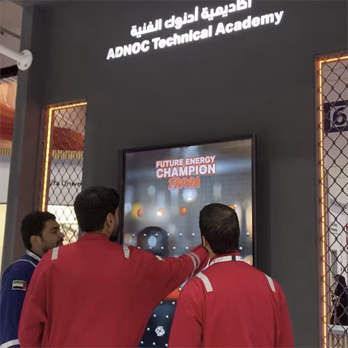 Students and guests play the Plinko Trivia Challenge at the ADNOC Technical Academy booth during a busy Dubai event