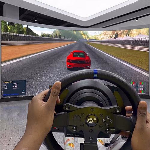 Woman using a pro-grade racing simulator setup with a high-precision wheel, pedals, black bucket seat, and large video screen showing a sports car track experience.
