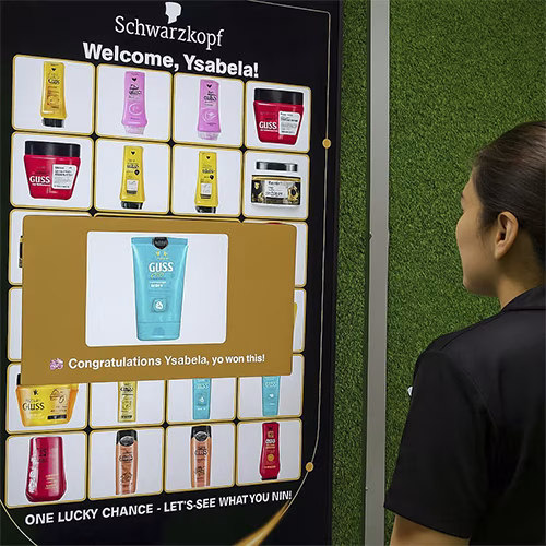 Guest playing Scan & Win interactive game by scanning QR code at a mall activation event in Dubai, with live name display and prize reveal on a big screen.