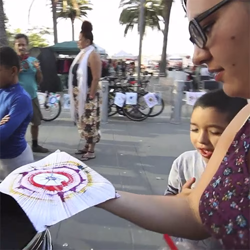 Guest pedaling the Spin Art Bike to create colorful artwork at an event, with vibrant paints splashing onto the spinning canvas.