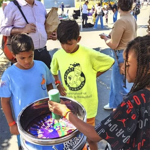 Guest pedaling the Spin Art Bike to create colorful artwork at an event, with vibrant paints splashing onto the spinning canvas.
