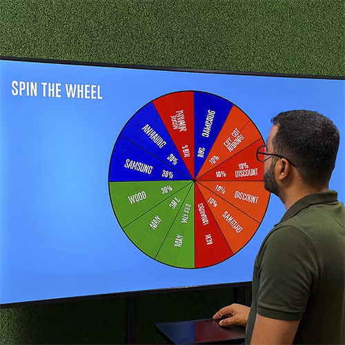 Arab male playing Spin the Wheel game at an exhibition event in Dubai, wearing traditional kandura, fully branded setup with digital screen and prize display, engaging crowd.