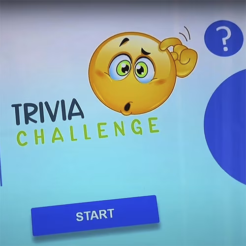 Touchscreen showing quiz results and a Dubai tower trivia question, with answer options and a person in a dark shirt standing beside the screen
