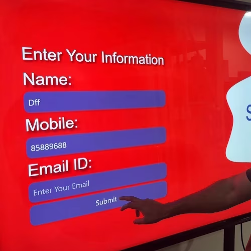Guest playing word scramble game on large touchscreen at Dubai event with branded graphics and green artificial grass wall background.
